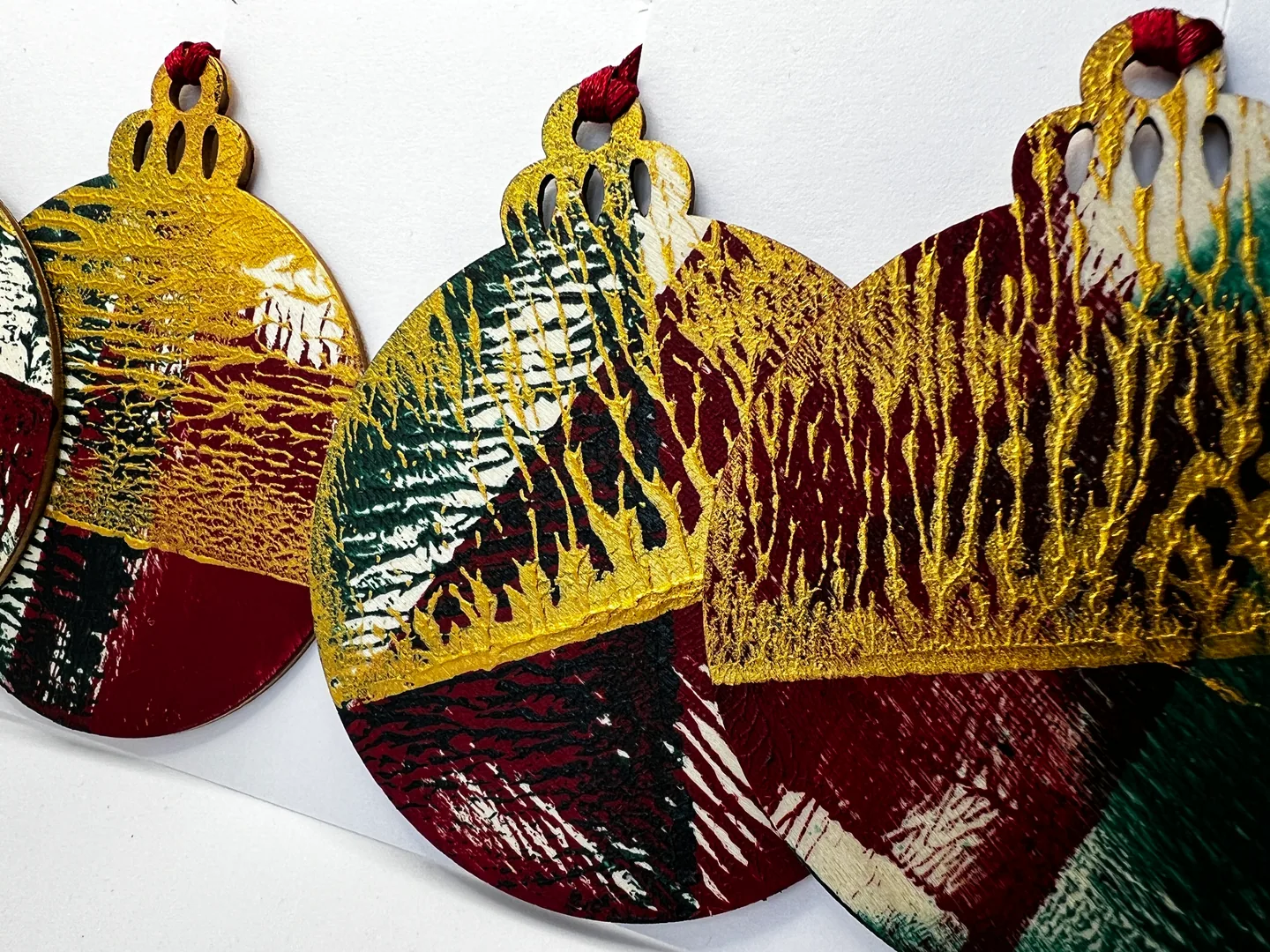 Close grouping of rounded hanging forms covered with dense ochre, burgundy, green, black and white patterns.