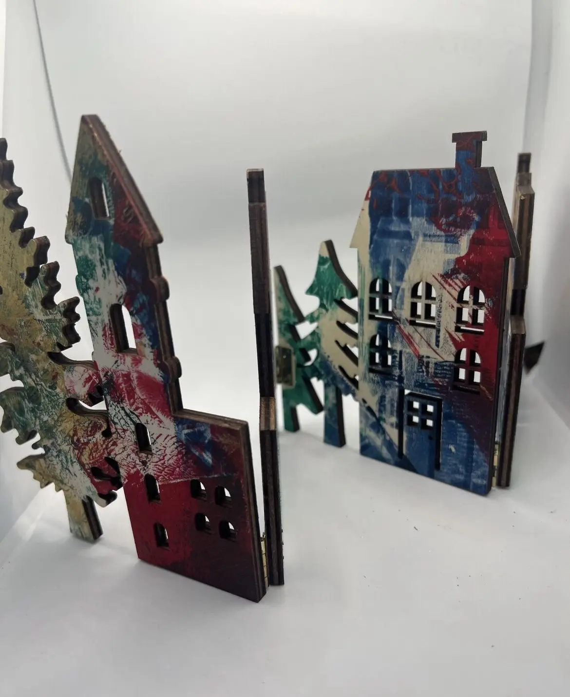 Layered house forms with cut-out windows and printed trees.