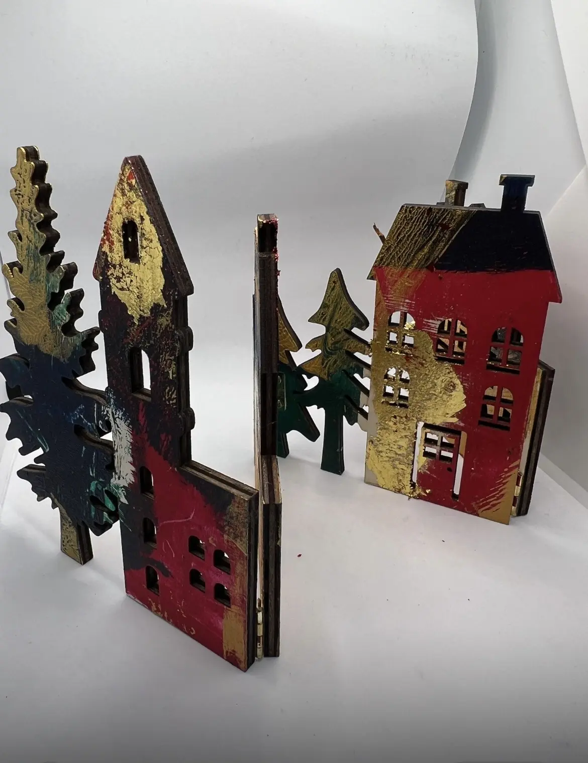 Winter village of handmade houses and trees in red, blue and gold.
